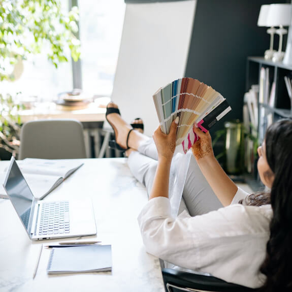 A woman sitting at a desk holding up color swatches